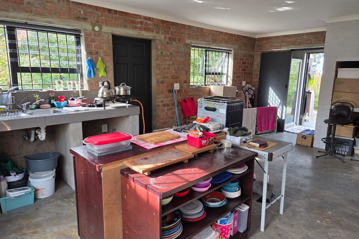 A rustic kitchen area featuring exposed brick walls, a concrete countertop with integrated sink, and direct access to the outdoor area.