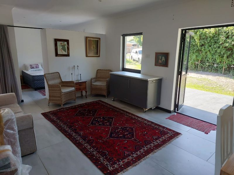 Open plan living area featuring tiled flooring, recessed lighting, and direct access to the rear garden through double glass doors.