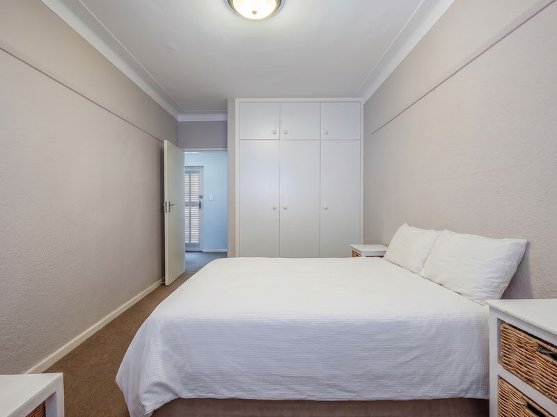 A well-maintained bedroom featuring neutral walls, carpeted flooring, and ample built-in cupboard storage space.