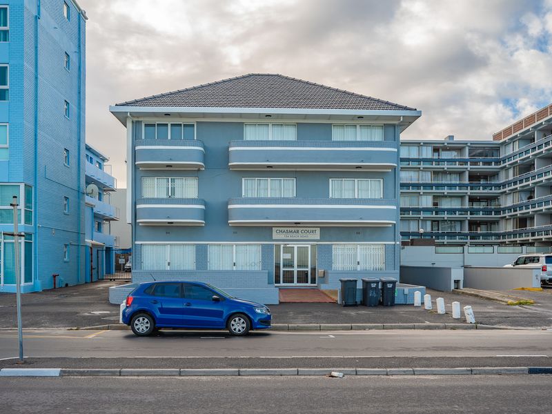 Front elevation of Chasmar Court apartment building, featuring a blue facade, multiple balconies, and a paved entrance area.