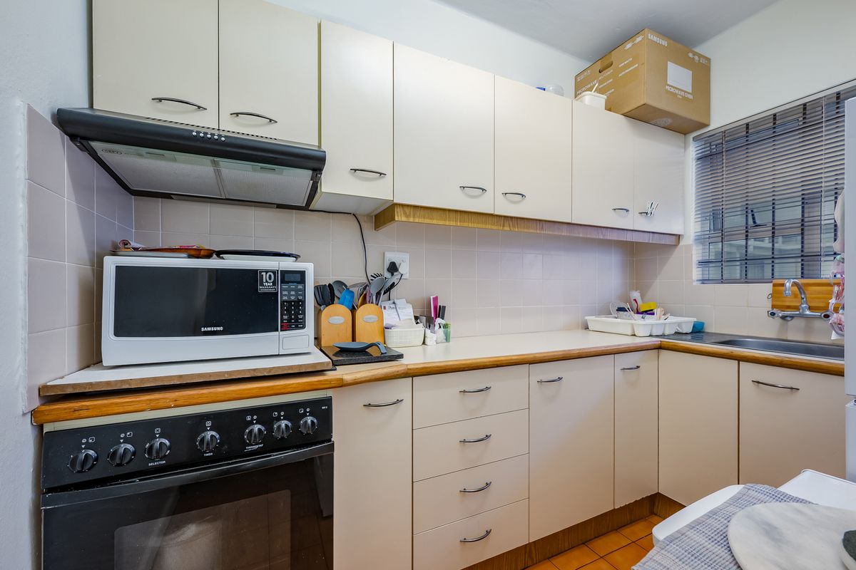 A functional kitchen featuring built-in cabinetry, laminate countertops, a tiled backsplash, and integrated oven with extractor fan.