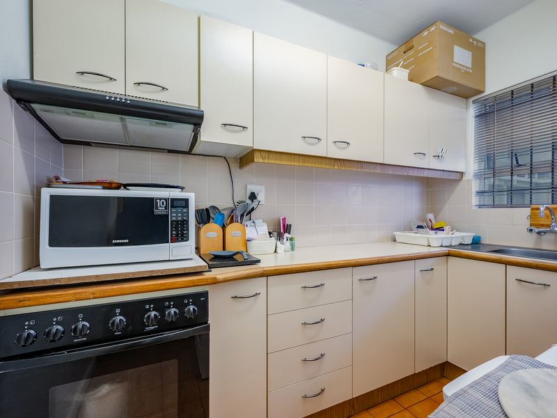 A functional kitchen featuring built-in cabinetry, laminate countertops, a tiled backsplash, and integrated oven with extractor fan.