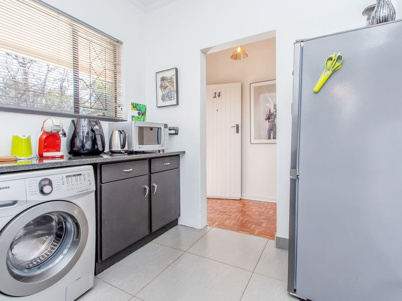 A functional laundry area featuring built-in cabinetry, stone countertops, and tiled flooring, providing convenient utility space with direct access to the interior hallway.