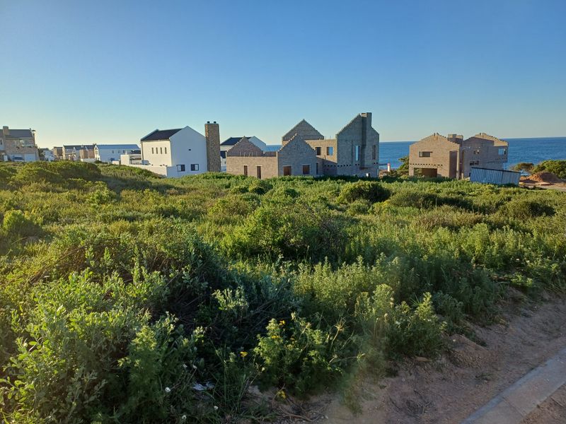 A view of residential vacant land featuring unfinished masonry structures set against a coastal landscape.