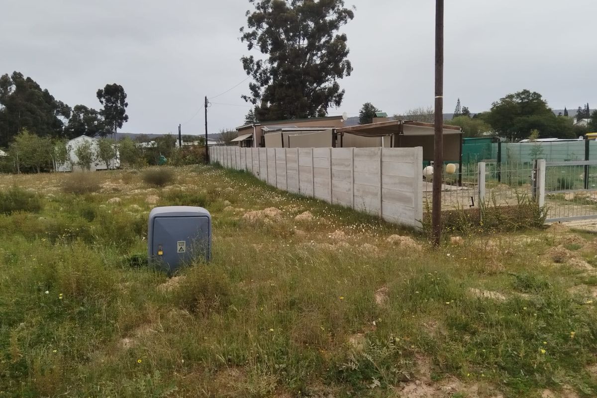 Vacant residential land featuring a precast concrete boundary wall, utility connection point, and established perimeter fencing.