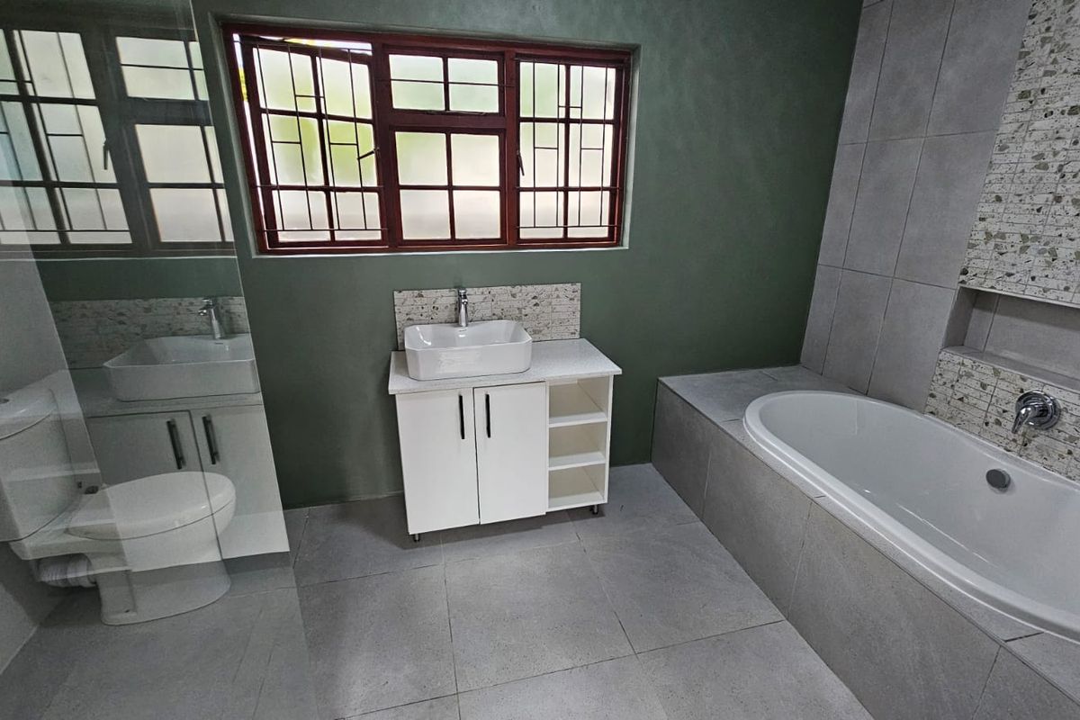 Modern bathroom featuring a vessel sink vanity, built-in bathtub, and tiled finishes, offering a clean and functional layout.