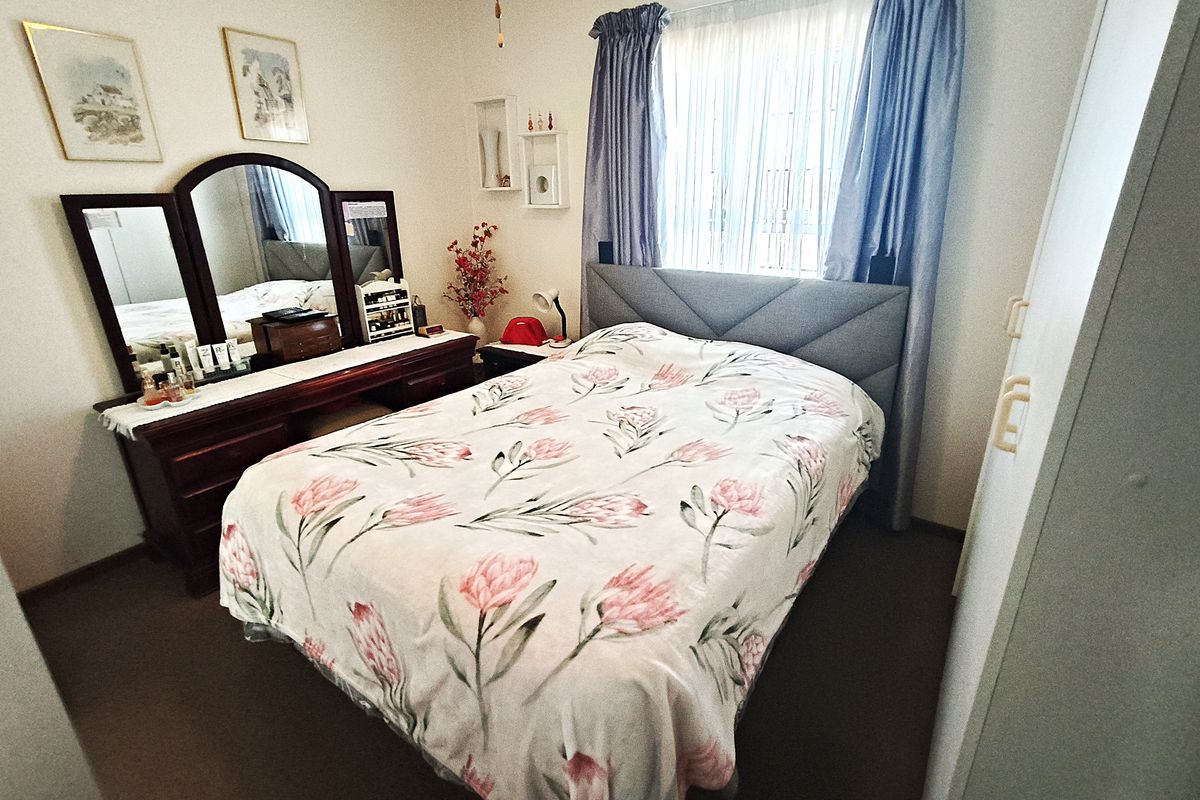 A functional bedroom featuring a built-in wardrobe and window with curtain tracks, providing a comfortable and well-lit sleeping space.