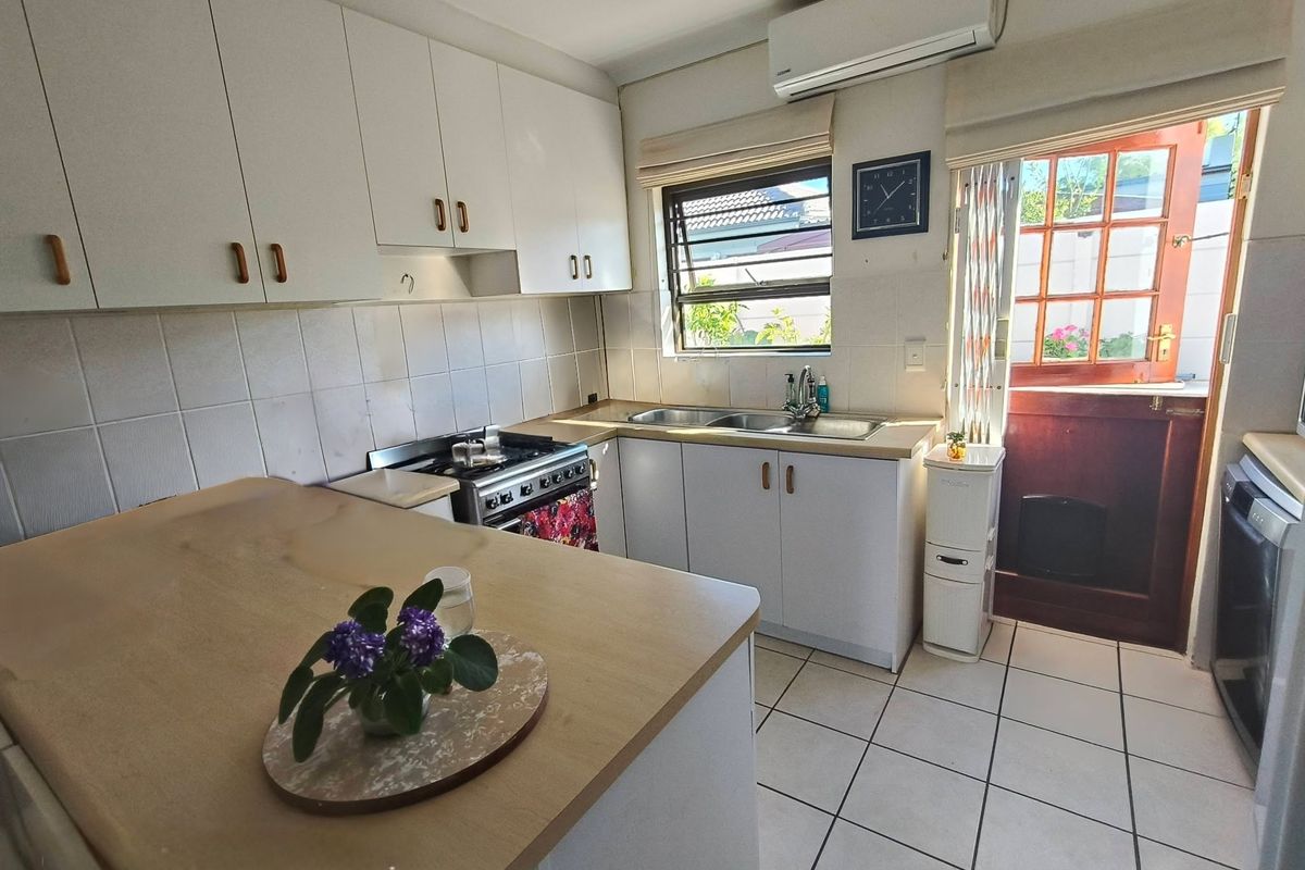 Functional kitchen featuring white cabinetry, tiled flooring, gas stove, and direct access to the rear exterior.