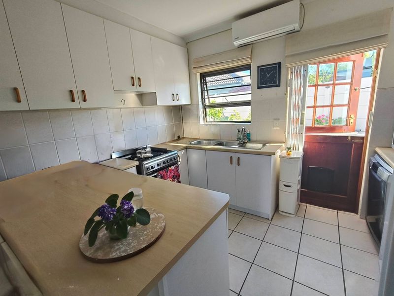 Functional kitchen featuring white cabinetry, tiled flooring, gas stove, and direct access to the rear exterior.