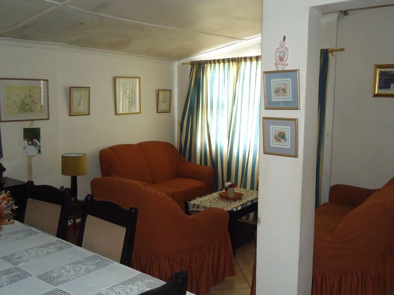 Open plan living and dining area featuring tiled flooring and a structural pillar, showing signs of ceiling water damage and wear.