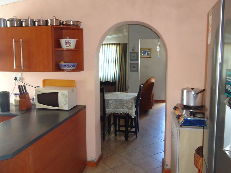 A functional kitchen featuring laminate cabinetry and countertops, connected to the dining area through a classic arched doorway with tiled flooring throughout.