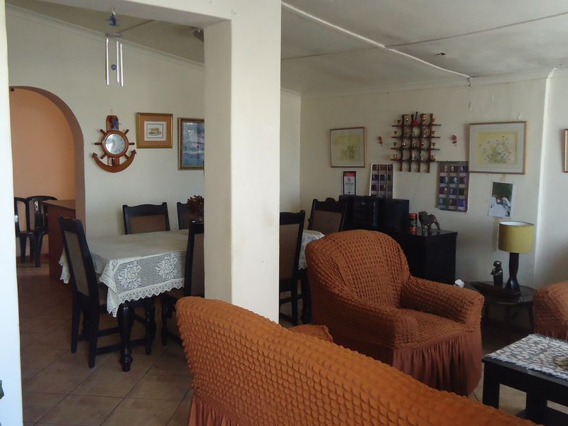 Open plan living and dining area featuring tiled flooring and a central structural pillar, with visible ceiling wear requiring maintenance.