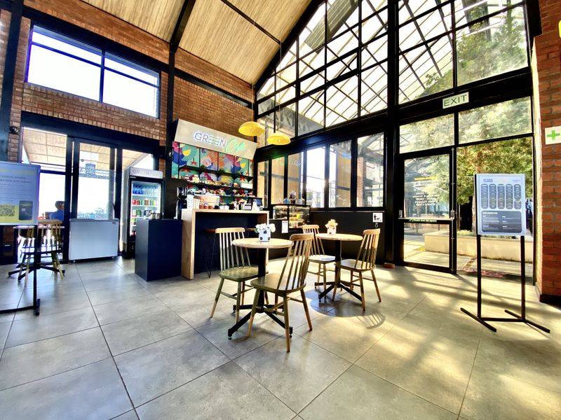 A bright, open-plan commercial space featuring high vaulted ceilings, exposed brick walls, and expansive steel-framed windows providing ample natural light.
