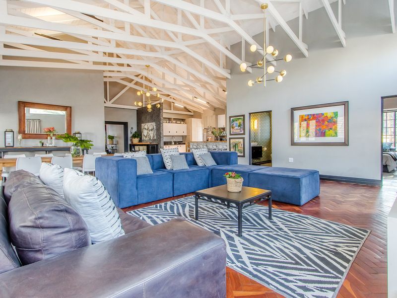 Spacious open-plan living area featuring high vaulted ceilings with exposed white timber trusses and elegant herringbone parquet flooring.