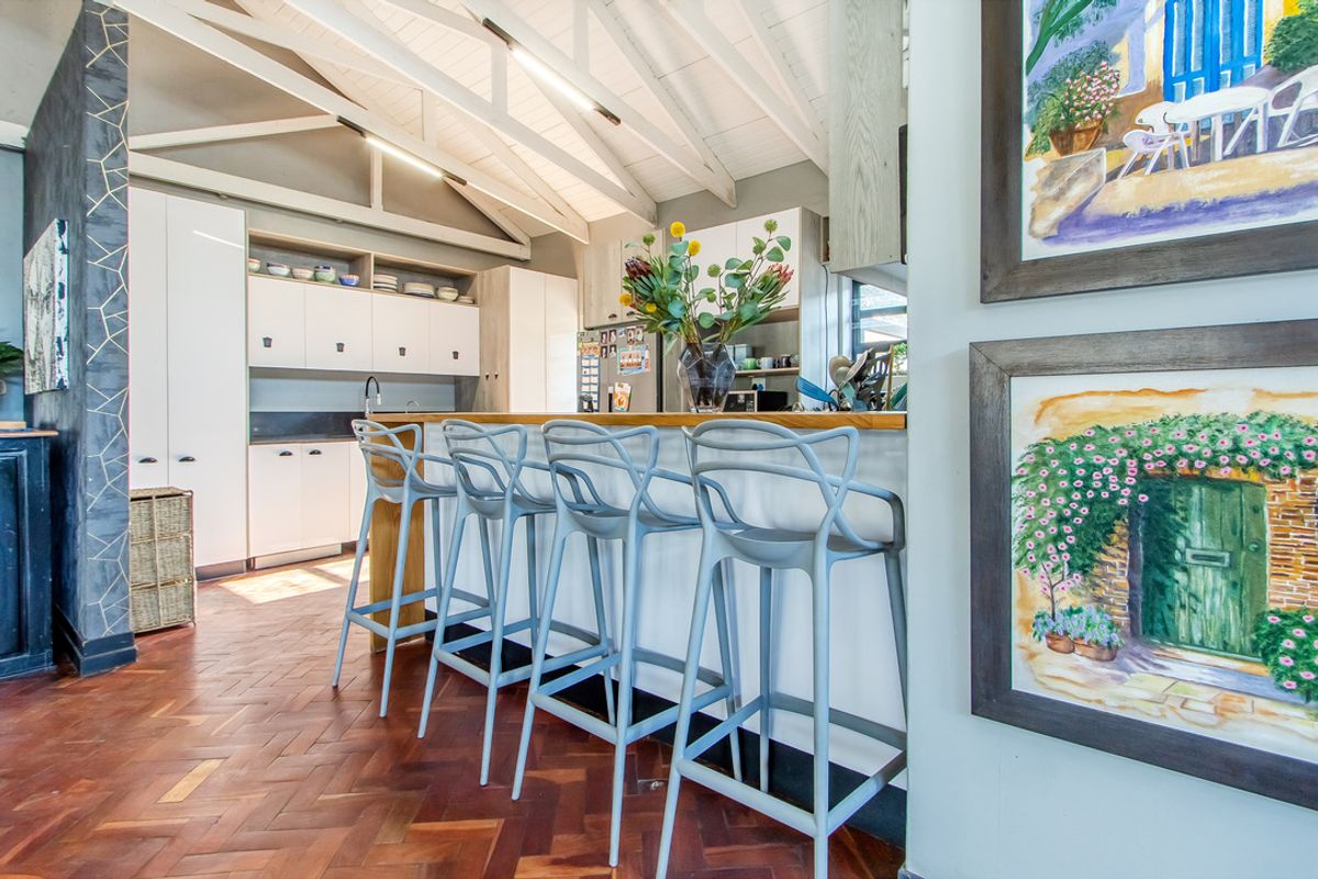 Modern kitchen featuring exposed timber rafters, herringbone parquet flooring, and a functional breakfast bar with a timber countertop.
