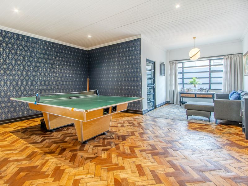 Spacious living area featuring classic herringbone parquet flooring, a decorative feature wall, and a high-quality tongue and groove ceiling with recessed lighting.