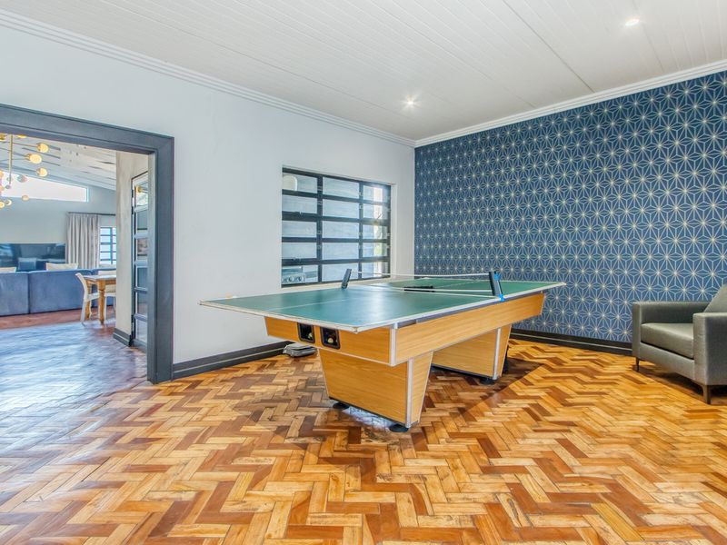Spacious living area featuring classic herringbone parquet flooring, a tongue and groove ceiling, and a striking geometric feature wall.