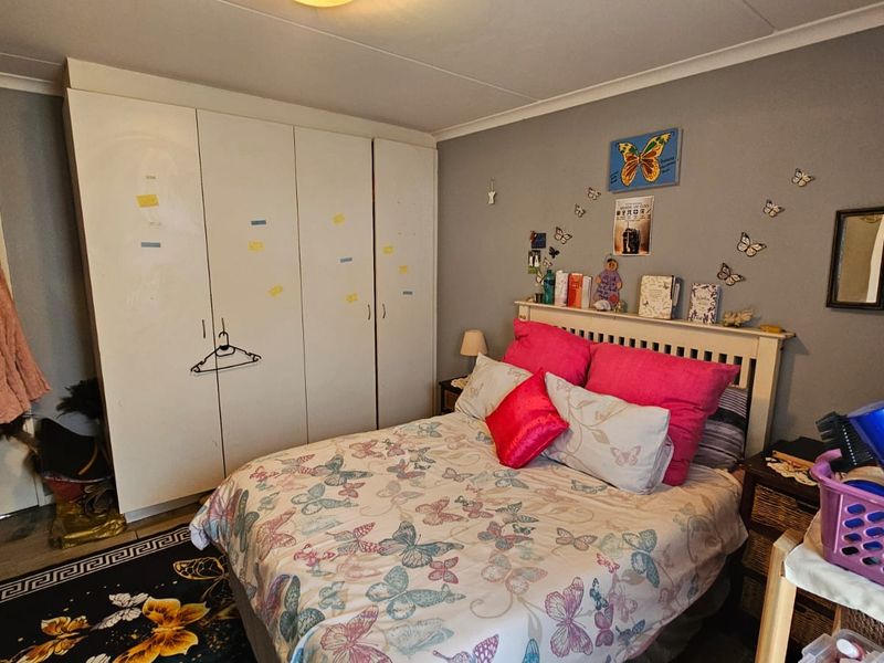 A bedroom featuring a large white built-in wardrobe and coved ceiling, providing functional storage space within the room.