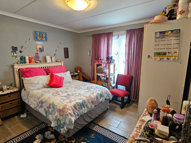 A functional bedroom featuring tiled flooring and a central ceiling light fixture, providing a comfortable living space.