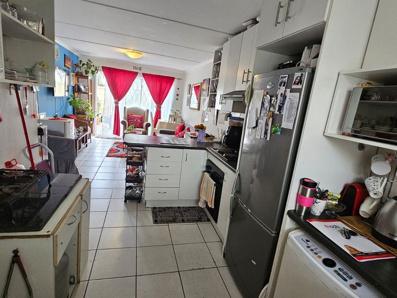 Open-plan kitchen and living area featuring tiled flooring, built-in cabinetry, and direct access to an outdoor space through a sliding door.