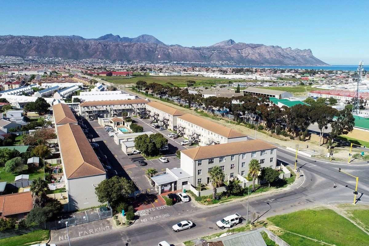 Aerial view of a residential apartment complex featuring multiple buildings, a communal swimming pool, and on-site parking facilities.