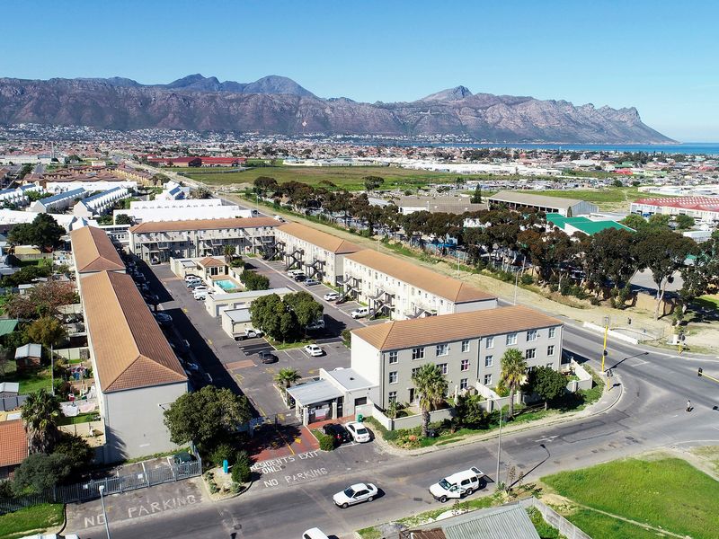 Aerial view of a residential apartment complex featuring multiple buildings, a communal swimming pool, and on-site parking facilities.