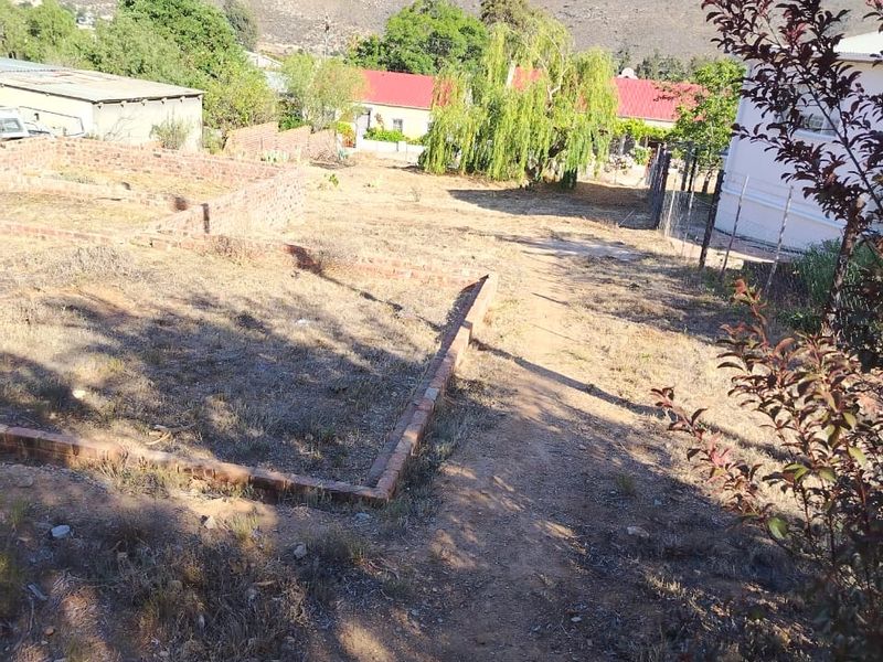 A view of a vacant residential plot featuring brick foundation footings and surrounding landscape with mountain views in the background.