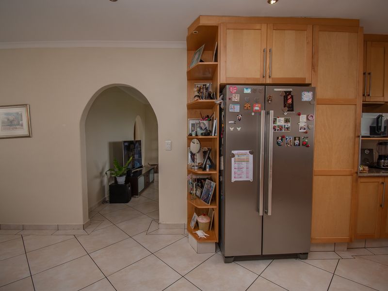 Kitchen area featuring light wood cabinetry, tiled flooring, and a distinctive arched doorway leading to the adjacent living space.