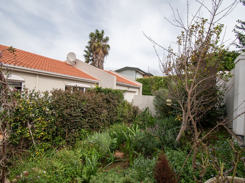 A view of the rear exterior of the house featuring a terracotta tiled roof and a landscaped garden area with established shrubs and trees.