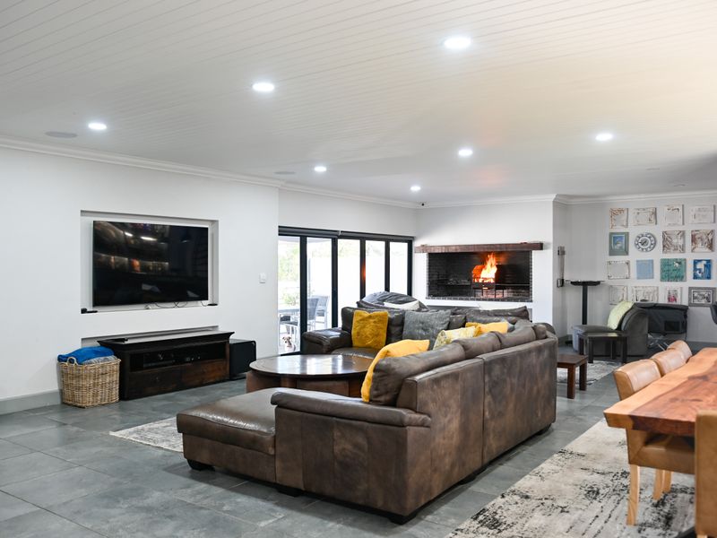 Spacious open-plan living area featuring tiled floors, recessed lighting, a tongue and groove ceiling, and a built-in fireplace with sliding door access to the outdoors.