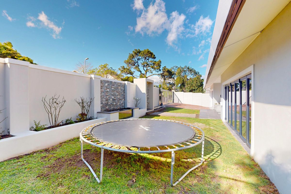 A well-maintained rear garden featuring a stone-clad feature wall, raised garden beds, and direct access to the home via large sliding glass doors.