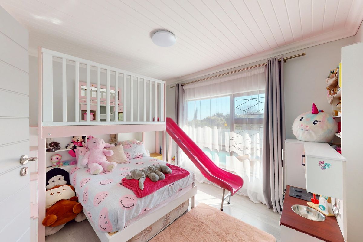 A bright bedroom featuring a tongue and groove ceiling, laminate flooring, and a large sliding window providing natural light.
