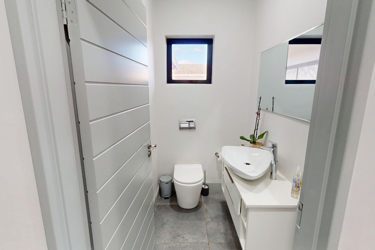 A modern, compact guest bathroom featuring a wall-hung toilet, a sleek vanity with a vessel sink, and contemporary grey floor tiles.