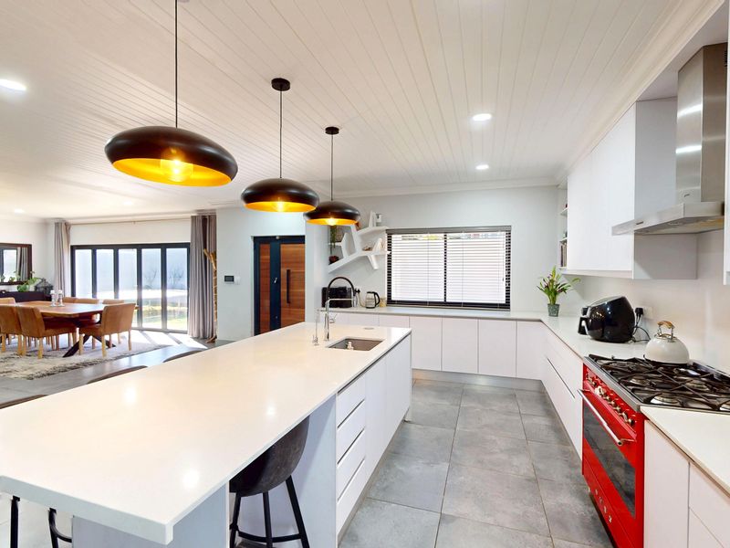 Modern open-plan kitchen and living area featuring a large island, quartz countertops, high-end gas appliances, and seamless flow to the outdoor patio.