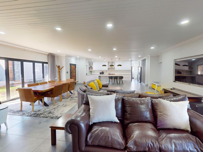 Spacious open-plan living, dining, and kitchen area featuring modern tiled floors, recessed lighting, and seamless access to the outdoor patio through bi-fold doors.