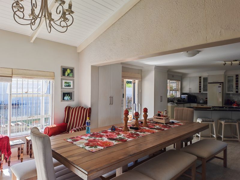 Spacious open-plan dining and kitchen area featuring a vaulted ceiling with exposed beams, built-in cabinetry, and a functional kitchen island layout.