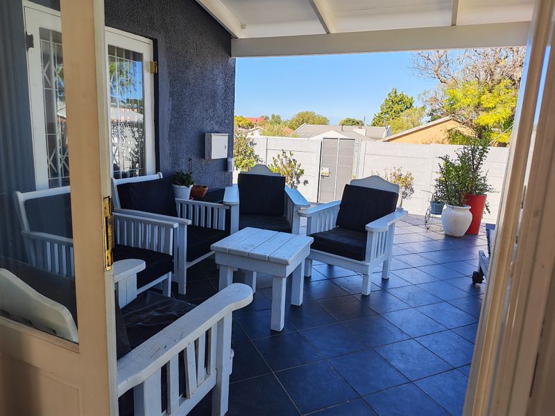 A covered outdoor patio area featuring dark tiled flooring and direct access to the rear garden space.