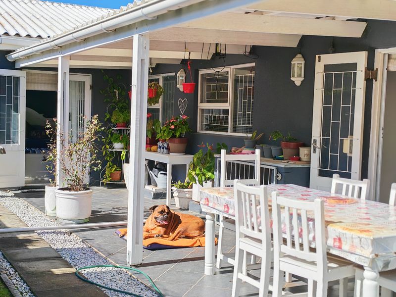 A covered outdoor patio area featuring tiled flooring and a timber pergola structure, providing a functional space for outdoor dining and relaxation.