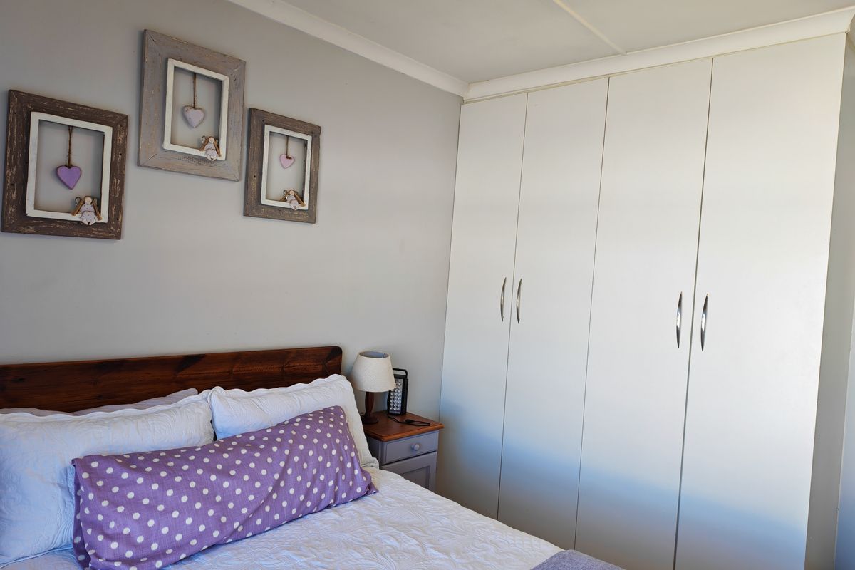 A well-maintained bedroom featuring neutral wall tones and ample built-in cupboard storage with modern hardware.