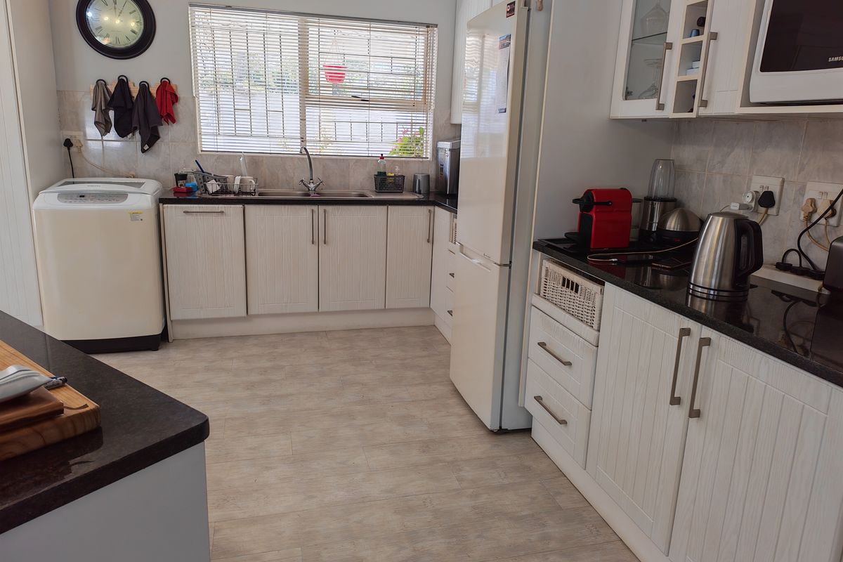 A functional kitchen featuring light-toned cabinetry, dark granite countertops, a double sink, and integrated microwave, offering a clean and practical workspace.