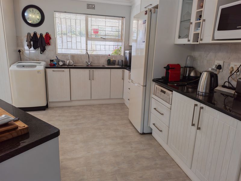 A functional kitchen featuring light-toned cabinetry, dark granite countertops, a double sink, and integrated microwave, offering a clean and practical workspace.