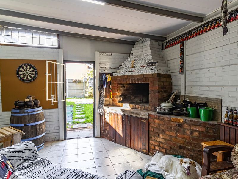Covered patio area featuring a built-in brick braai, tiled flooring, and direct access to the rear garden.