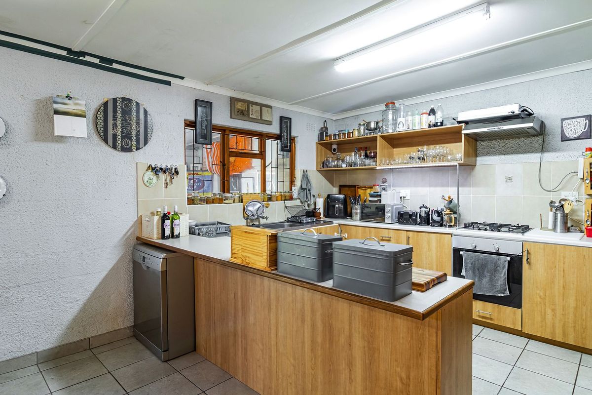 Functional kitchen featuring wood-look cabinetry, gas hob, built-in oven, extractor fan, and tiled flooring with a practical layout.