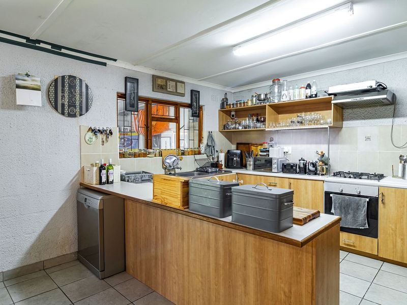 Functional kitchen featuring wood-look cabinetry, gas hob, built-in oven, extractor fan, and tiled flooring with a practical layout.