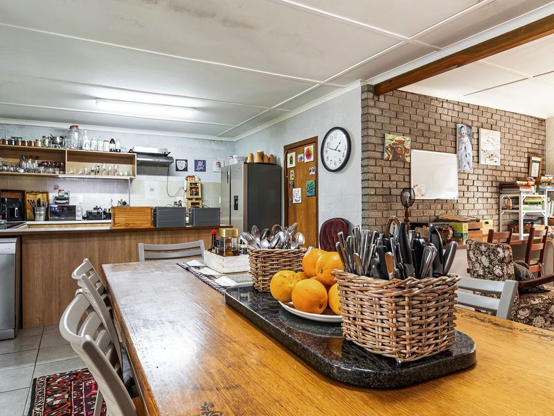 Open-plan kitchen and dining area featuring exposed brickwork, tiled flooring, and functional cabinetry, offering a versatile space for family living and entertaining.