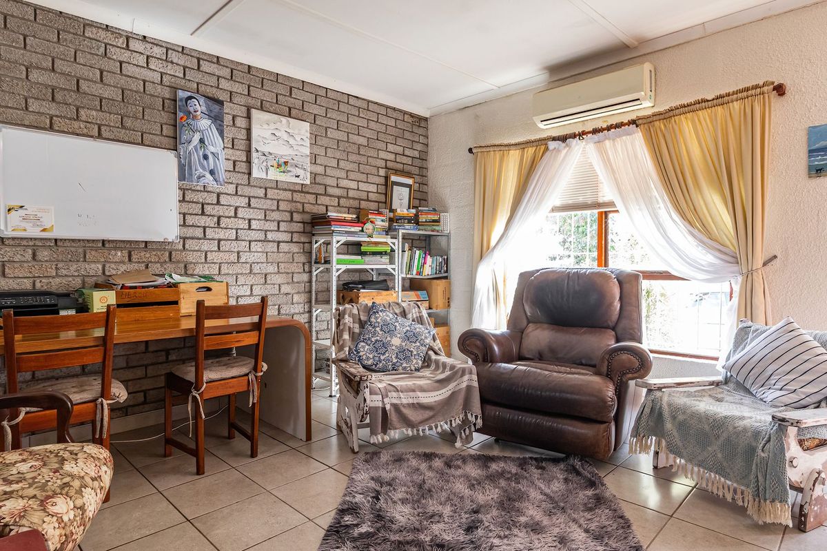 A living area featuring an exposed brick feature wall, tiled flooring, and a wall-mounted split system air conditioner.