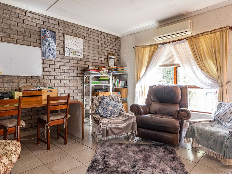 A living area featuring an exposed brick feature wall, tiled flooring, and a wall-mounted split system air conditioner.