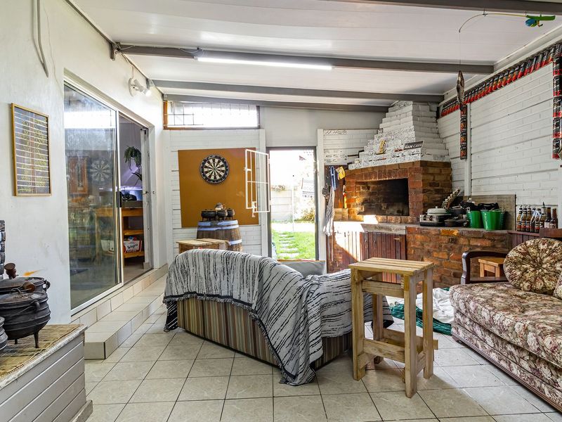 Covered patio area featuring a built-in brick braai, tiled flooring, and sliding door access to the main house interior.