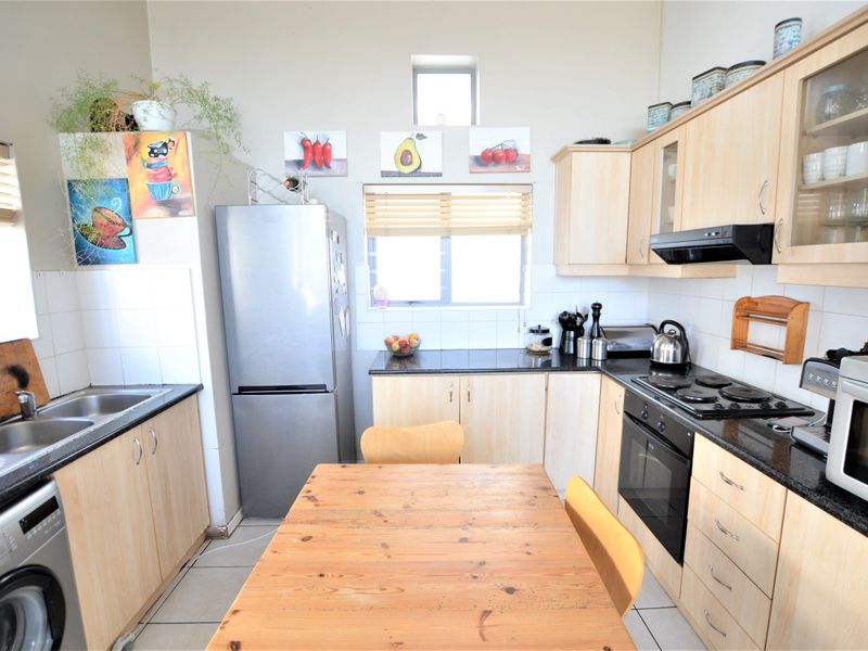 A functional kitchen featuring light wood-finish cabinetry, granite countertops, a double basin sink, and built-in cooking appliances with a tiled backsplash.
