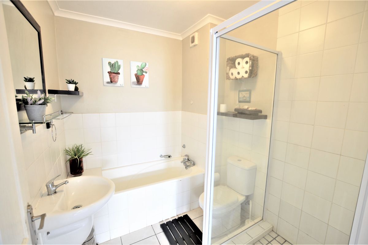 A functional bathroom featuring a pedestal basin, built-in bathtub, and a separate shower enclosure with tiled finishes.